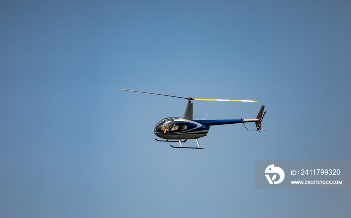 Robinson 44 Raven II helicopter at flight on clear blue sky