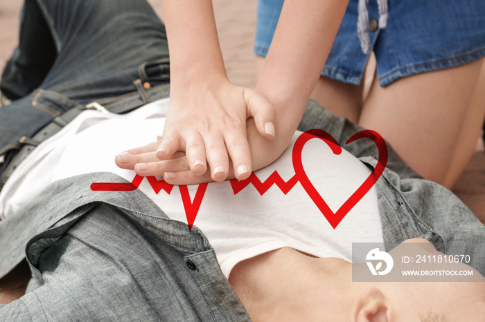 Woman giving first aid to young man with heart attack on street