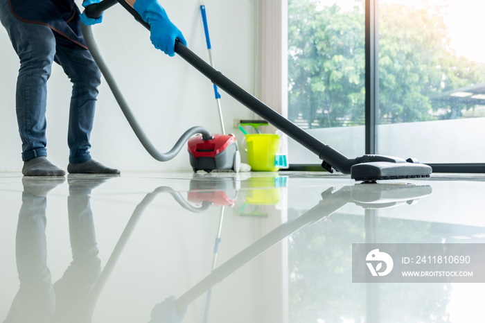 Young attractive man is cleaning vacuum commercial cleaning equipment on floor at home helping wife.