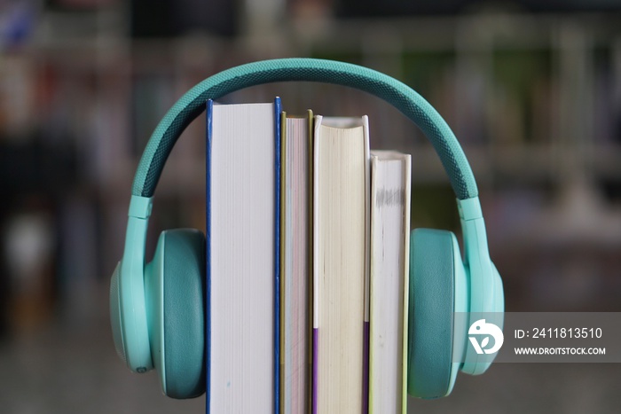 soft focus of the books stacked up with headphone on bookshelf background.