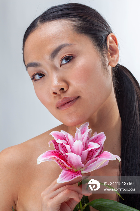 Studio portrait of woman holding white and�purple lily flower