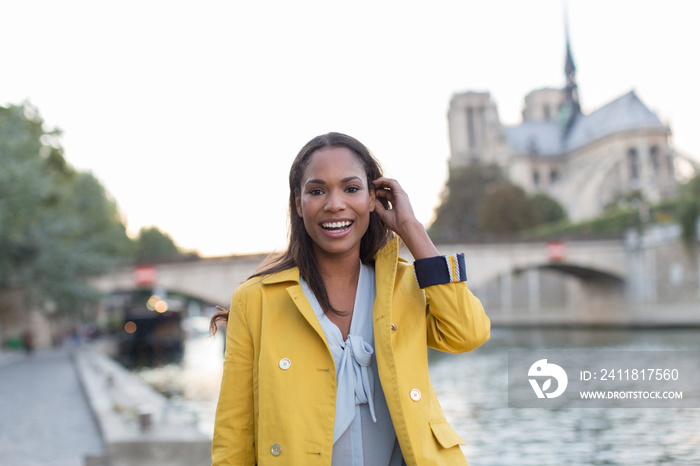 Portrait confident young woman walking along Seine River, Paris