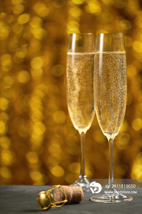 Two glasses of champagne on golden bokeh background