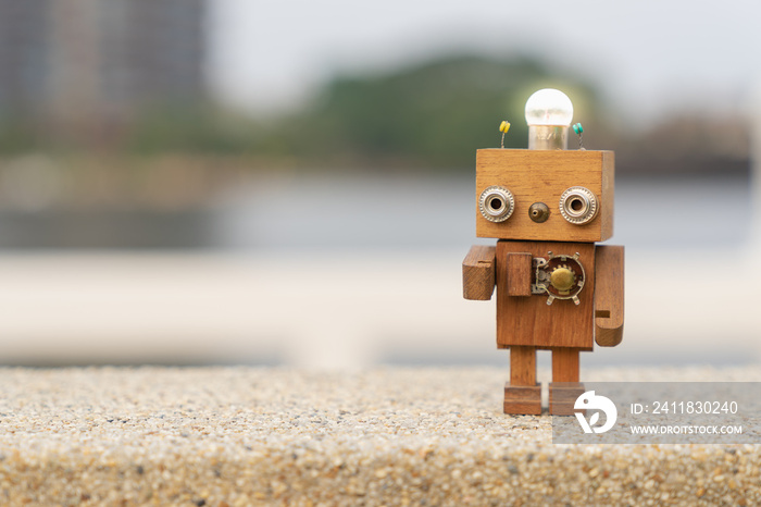 Retro wood robot with light bulb on the head standing on the table with blur nature background, natu