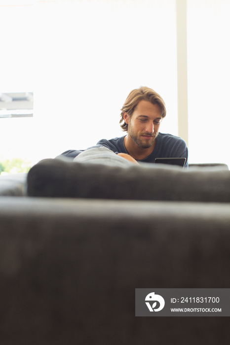 Young man using digital tablet on sofa