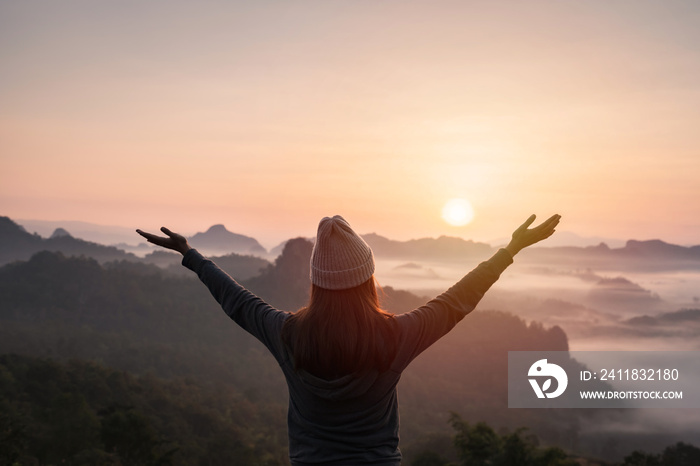 Young woman traveler looking at sea of mist and sunset over the mountain