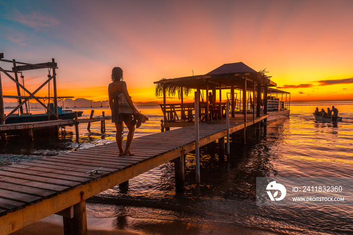 A young tourist in a sunset on a pier on a beach on Roatan Island. Honduras