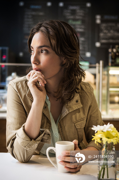 Thoughtful woman holding coffee mug in cafe