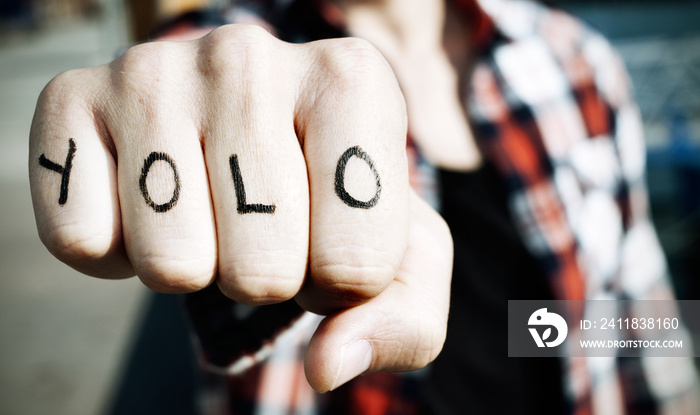 young man with the word yolo in his knuckles, filtered