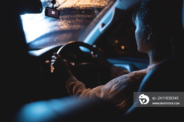 一个亚洲女人在夜里独自开车。天在下雨。