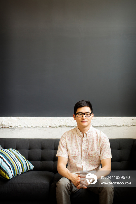 Portrait of man wearing eyeglasses sitting on sofa at home