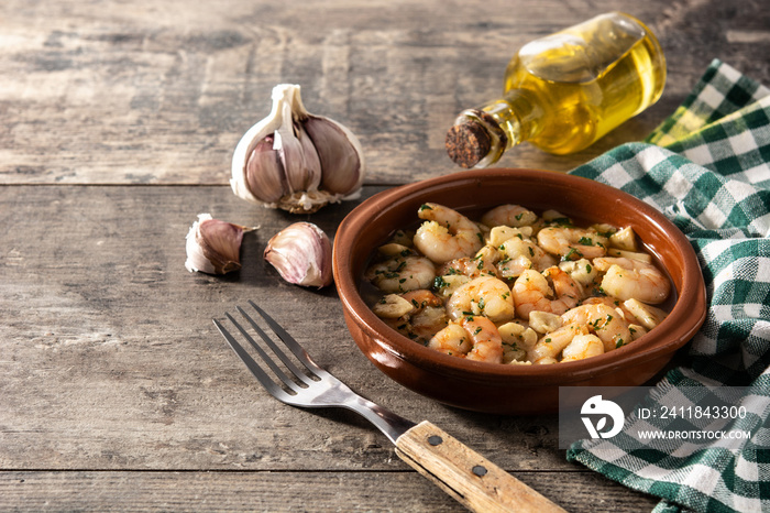 Garlic prawns in crockpot on wooden table.Copy space