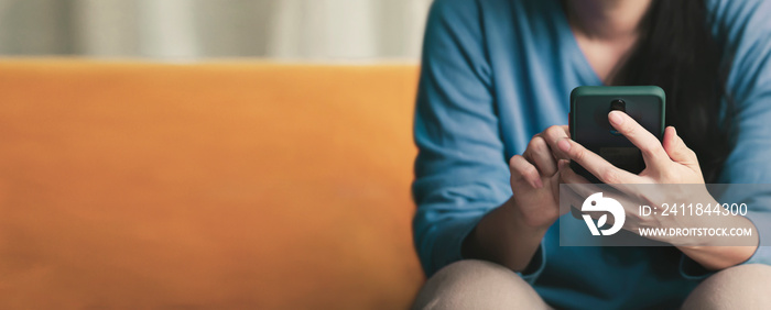 Young teen using mobilephone chatting with friend on yellow sofa