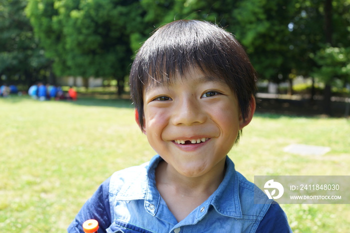 乳歯　生え変わり　シロツメクサと少年　クローバー　芝生　公園　1年生　小学生　夏休み　春休み　花摘み　平和　しゃがむ