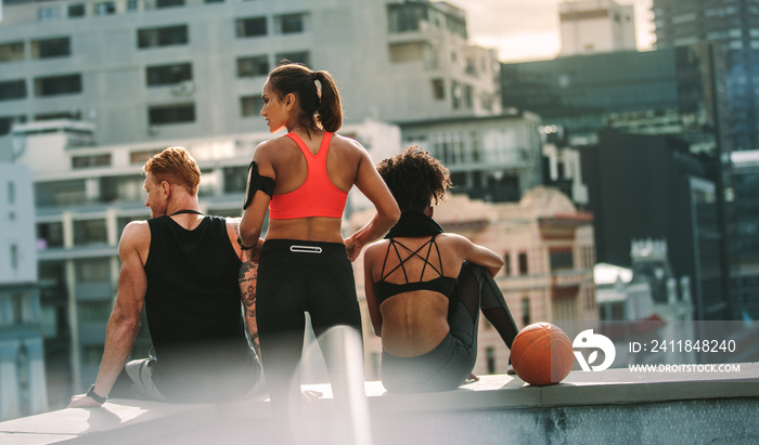 Rear view of athletic man and women sitting on rooftop