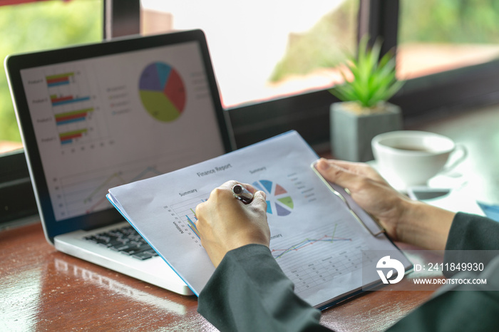 Business woman working at office with laptop, tablet and graph data documents on his desk, Analyze s