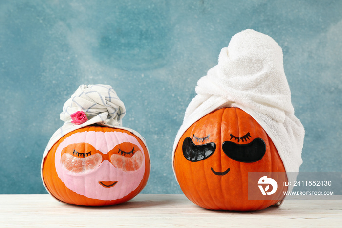 Pumpkins with eye patches and towels on blue background