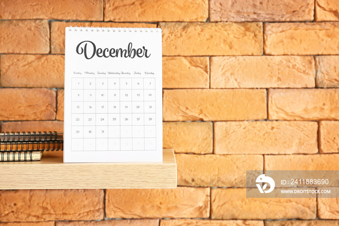 Shelf with flip paper calendar on brick wall