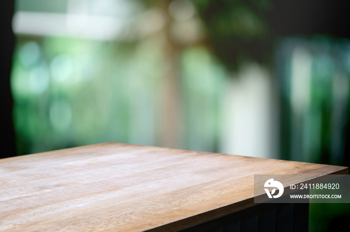 empty wooden table top with blur coffee shop or restaurant in green garden background