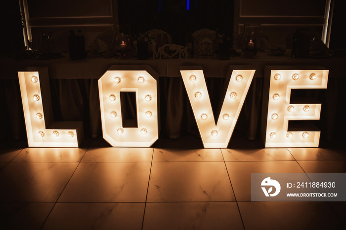 Wooden glowing love text letters. Rustic wedding dance floor lamp.