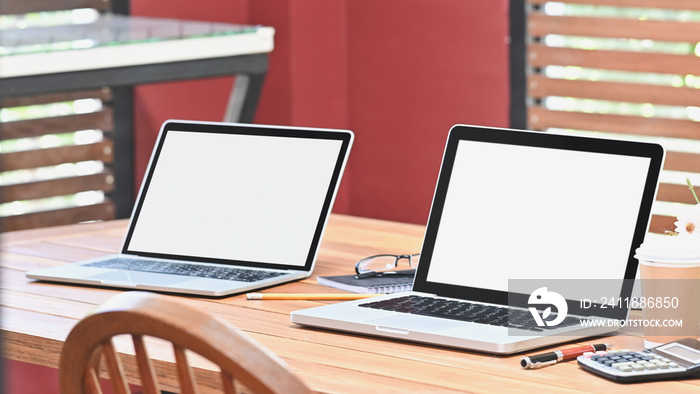 Communication workspace two device laptop computer with empty screen on table.