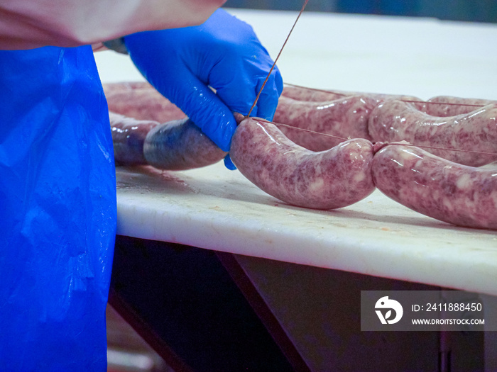 worker manufacturing, stuffing and tying sausages, salme and chorizo in cured meats production facil