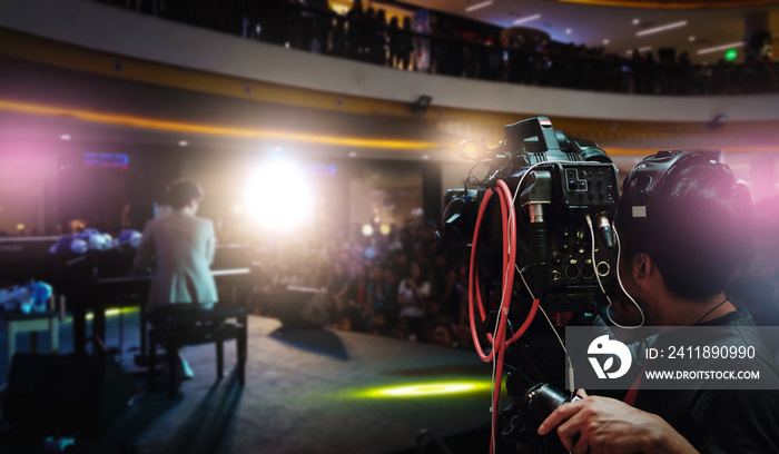 Video photographer using camcorder to record the artist plays the piano on stage in hall