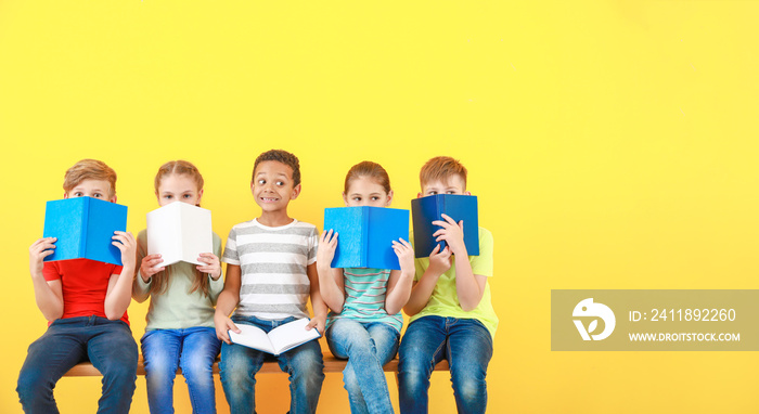 Cute little children with books on color background