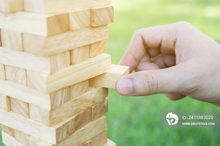 游戏jenga，人的手在玩的特写，在塔上玩一块木头堆叠游戏