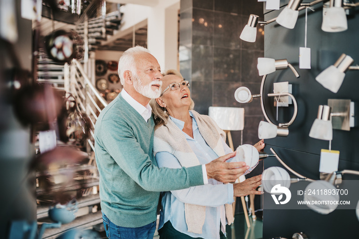 Senior couple in home lighting store shoosing shandelier for their home