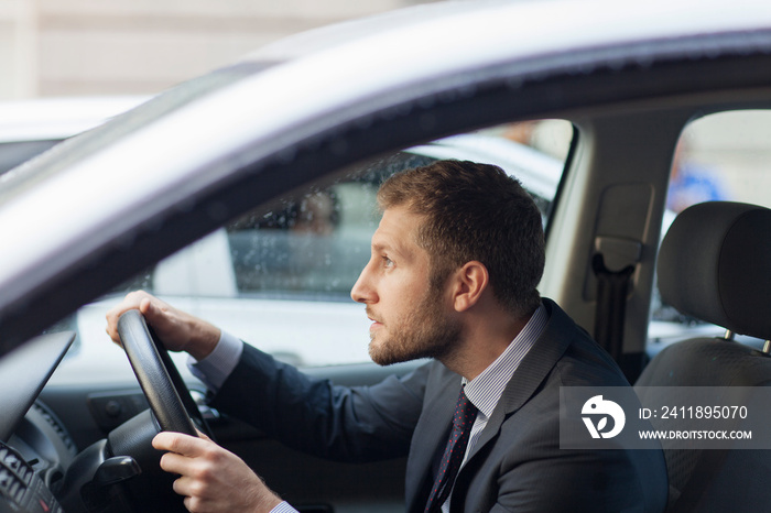 Worried businessman driving car in rain