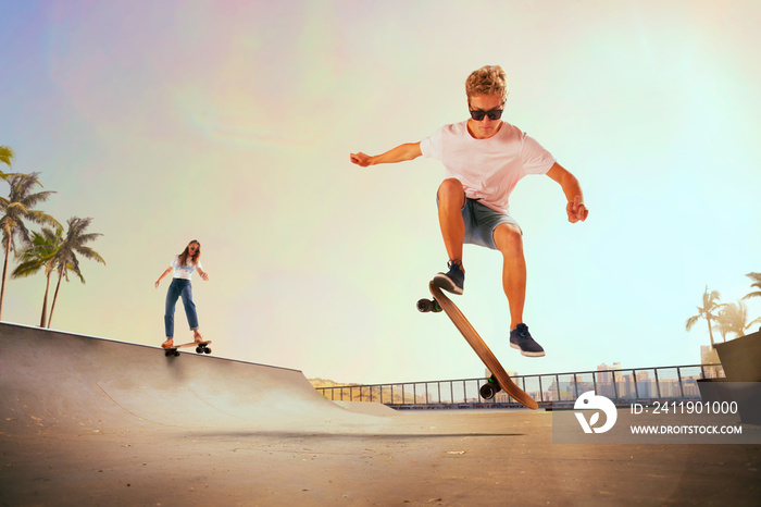 Skateboarder is performing tricks in skatepark on sunset.