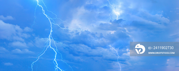 Lightning strikes between blue stormy clouds.