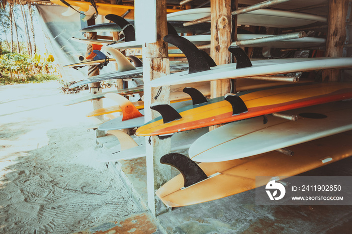 Set of different colorful surf boards in a stack available for rent on the beach. vintage color tone