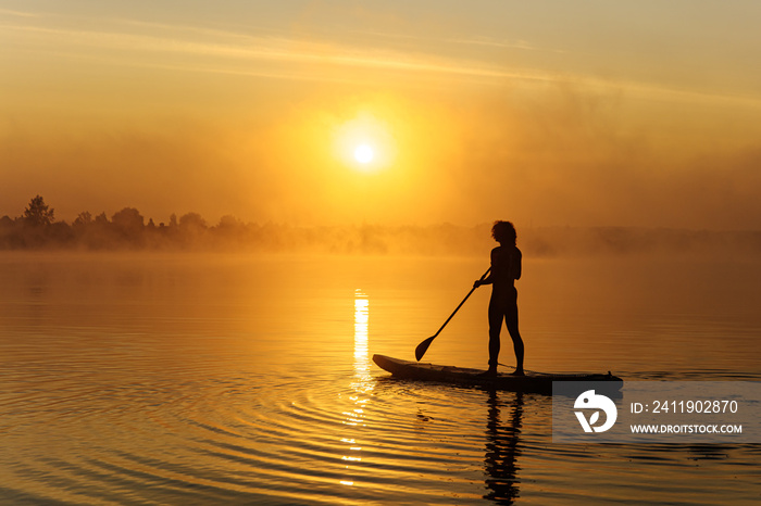 Young man doing surfing on sup board during sunrise