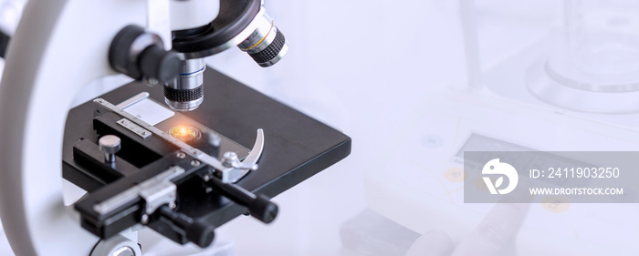 Close-up shot of microscope with laboratory equipment background