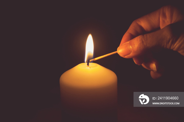 Vintage tone of hand with matchstick, lighting a candle