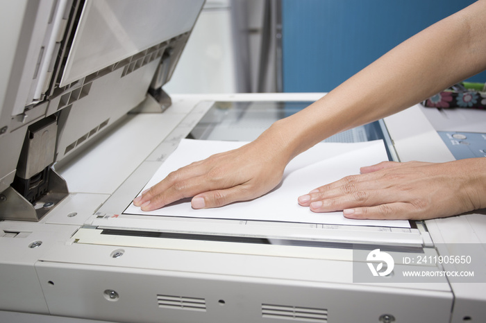 woman hands putting a sheet of paper into a copying device