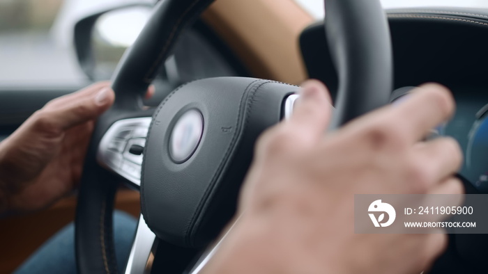 Closeup male putting hands on steering wheel. Man holding steering wheel at car