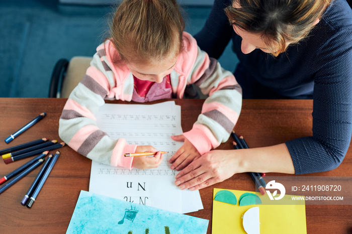 Little girl preschooler learning to write letters with help of her mother. Kid writing letters, draw