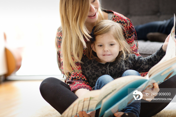 Mother and daughter (4-5) reading picture book