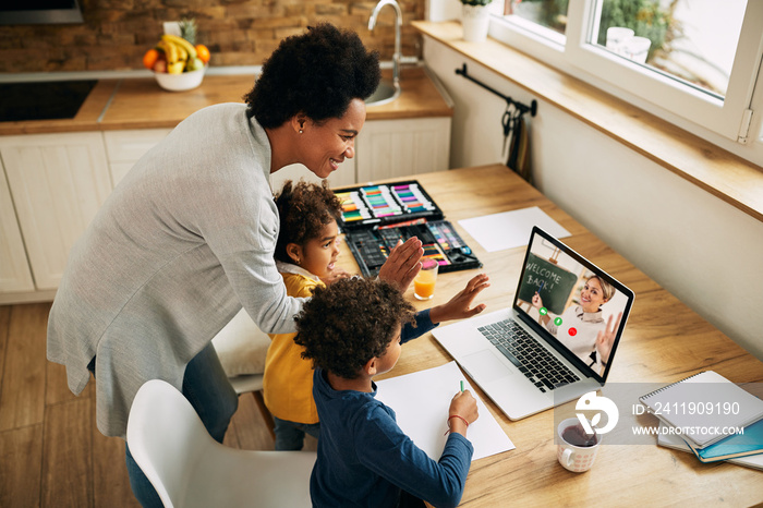 Happy African American family greeting a teacher during a video call over laptop.