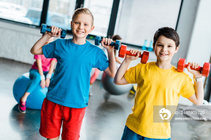 Cheerful boys laughing while training with dumbbells