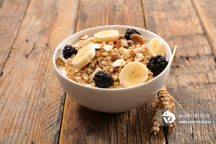 muesli, cereal with banana and blackberry on wood background