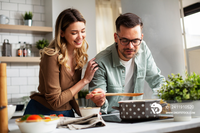 Happy smiling couple cooking together. HUsband and wife preparing fresh meal at home.