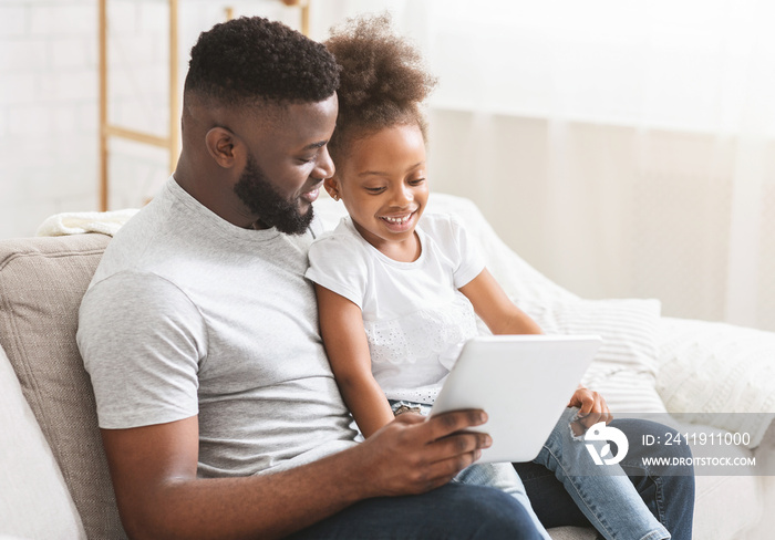 Afro dad and little daughter using digital tablet at home