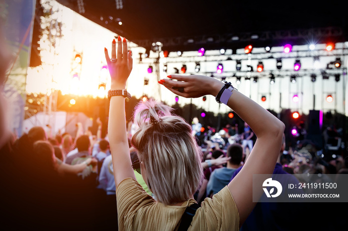 People with raised hands at summer music festival.