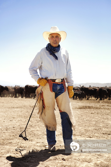 Portrait of cowboy holding farrier while standing in ranch