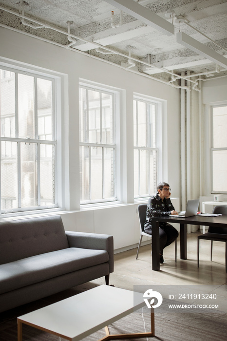 Side view of businesswoman using laptop computer while sitting in office