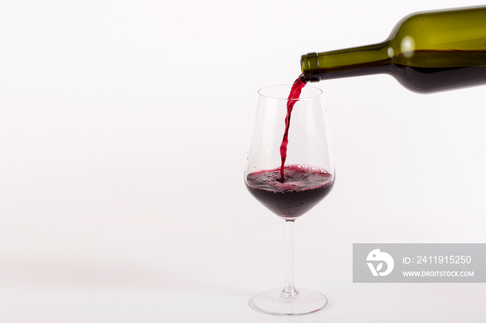 红酒倒入白底隔离的玻璃杯